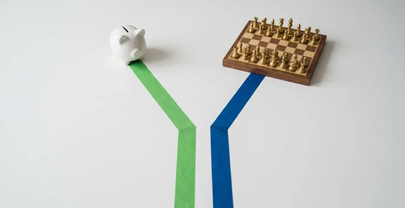 Deux chemins tracés sur une table blanche : un ruban vert vers une tirelire, un ruban bleu vers un échiquier, symbolisant le choix entre épargne et crédit.